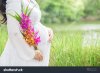 stock-photo-pregnant-woman-carry-her-belly-and-colorful-flower-in-the-fresh-garden-451042702.jpg
