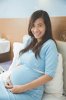 45151340-Asian-pregnant-happy-Woman-sitting-on-the-bed-smiling-to-the-camera.jpg