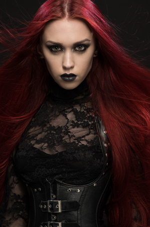 70794140-young-woman-with-red-hair-in-black-gothic-costume-on-dark-background.jpg